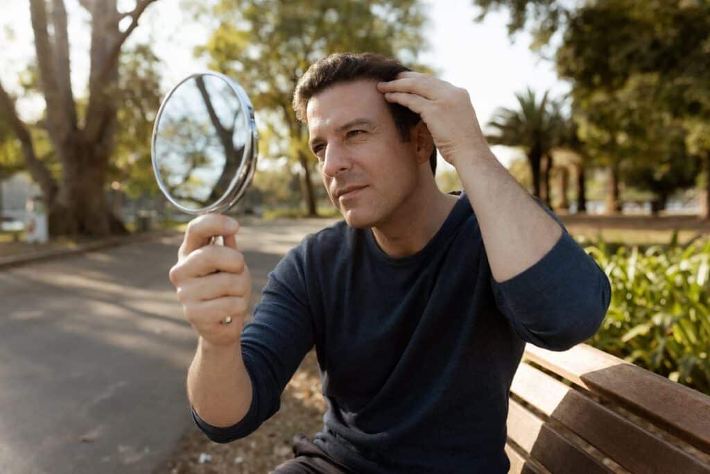 Man checking Botox results on forehead in mirror at Miami Lakes park