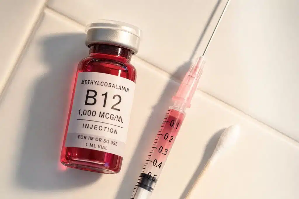 Methylcobalamin B12 vial and syringe arranged on clean white tile for wellness injections at Miami Lakes Med Spa