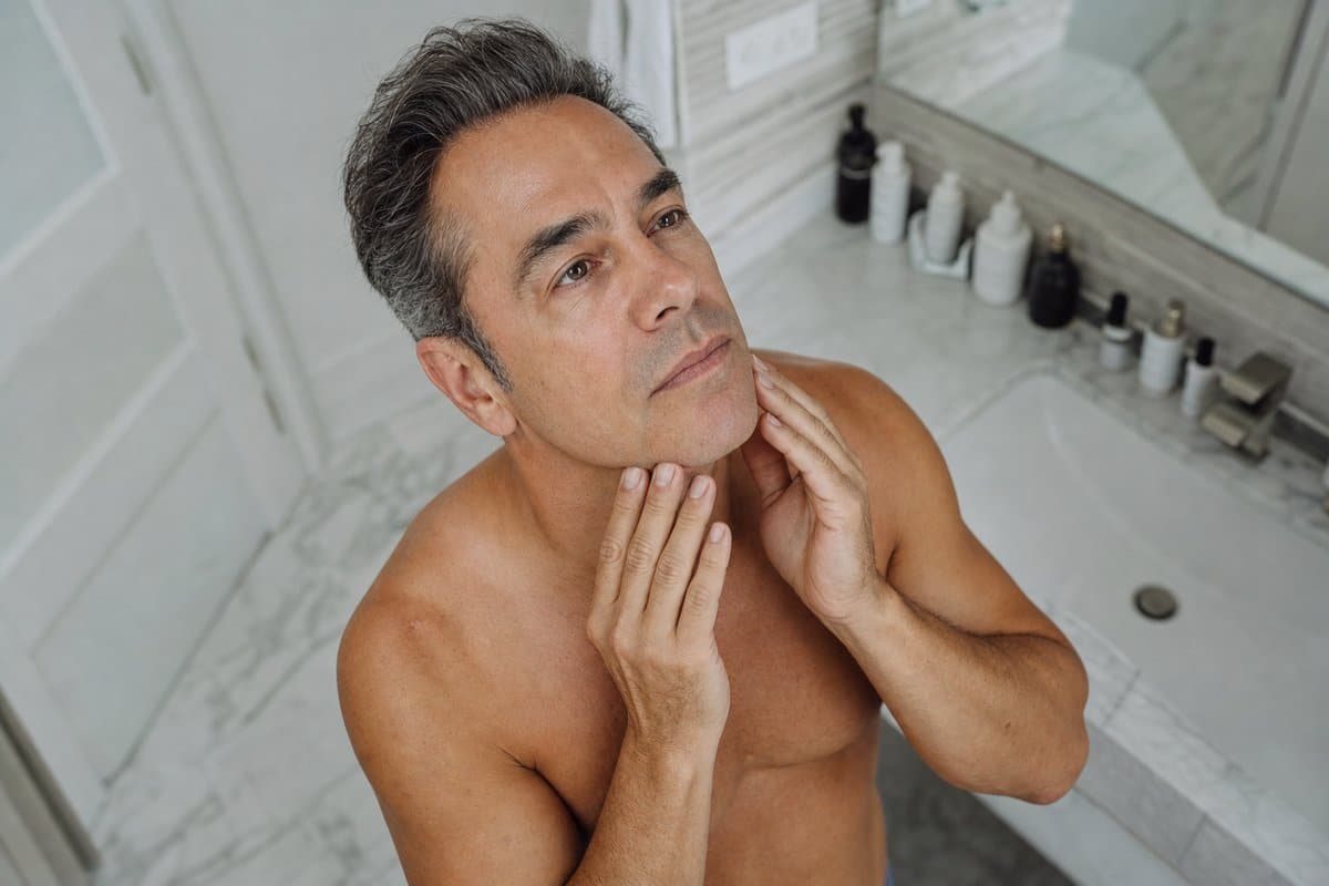 Man in his late 40s touching his smooth jawline and neck after face laser hair removal in Miami Lakes