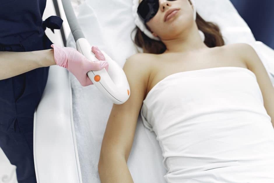 Female clinician in plum scrubs performing laser hair removal on a patient's underarm with the Candela GentleMax Pro Plus at Miami Lakes Med Spa