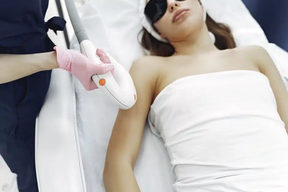 Female clinician in plum scrubs performing laser hair removal on a patient's underarm with the Candela GentleMax Pro Plus at Miami Lakes Med Spa
