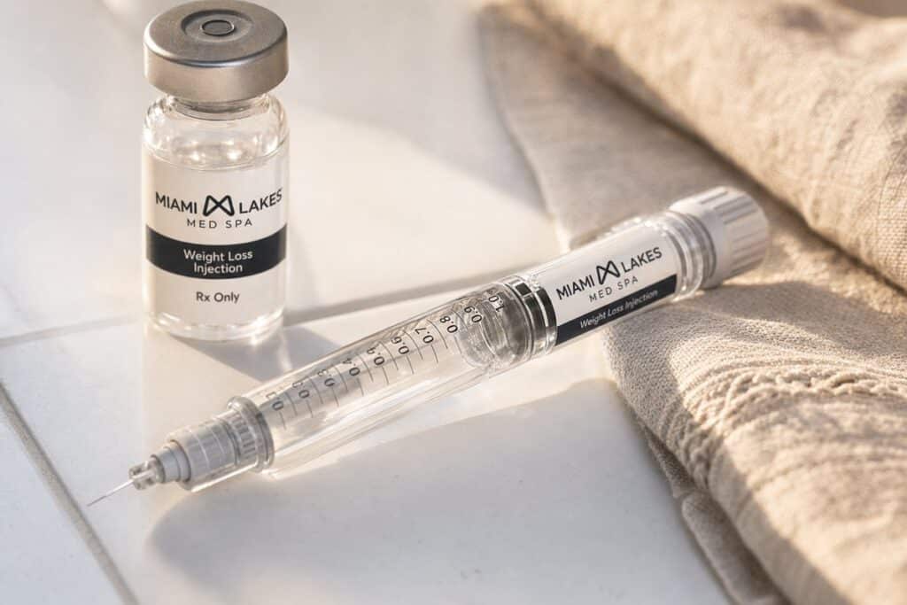Macro close-up of semaglutide and tirzepatide weight loss injection syringe and vial on white tile