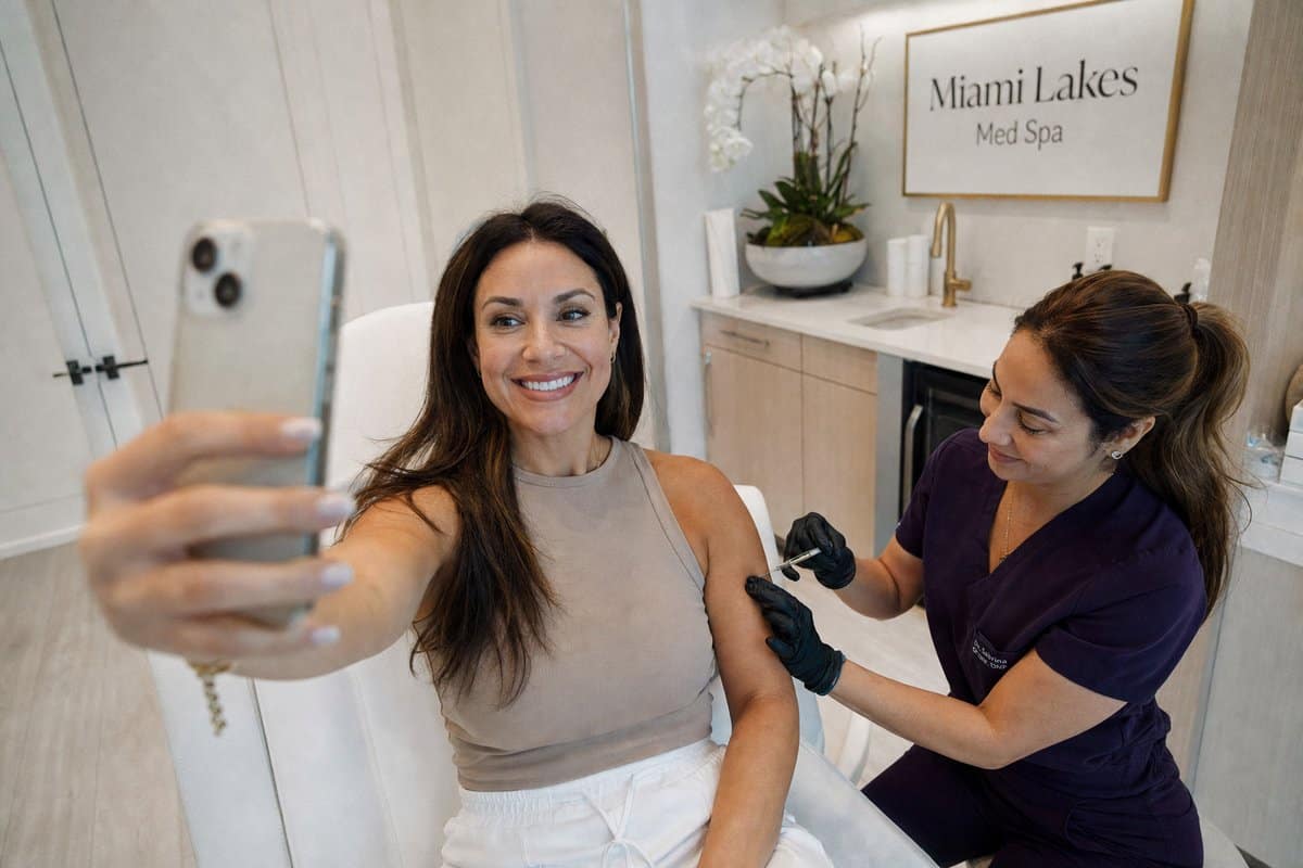 Woman in her late 30s taking a glowing selfie showing her energized skin and toned arm after wellness injections