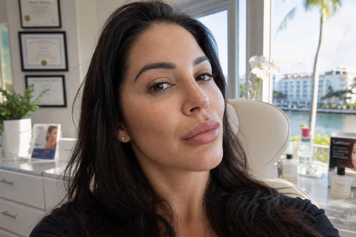 Woman taking a selfie showing natural-looking lip filler and cheek filler results