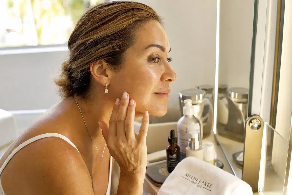 Woman in her 40s examining smooth, refreshed cheek and jawline skin after microneedling treatment