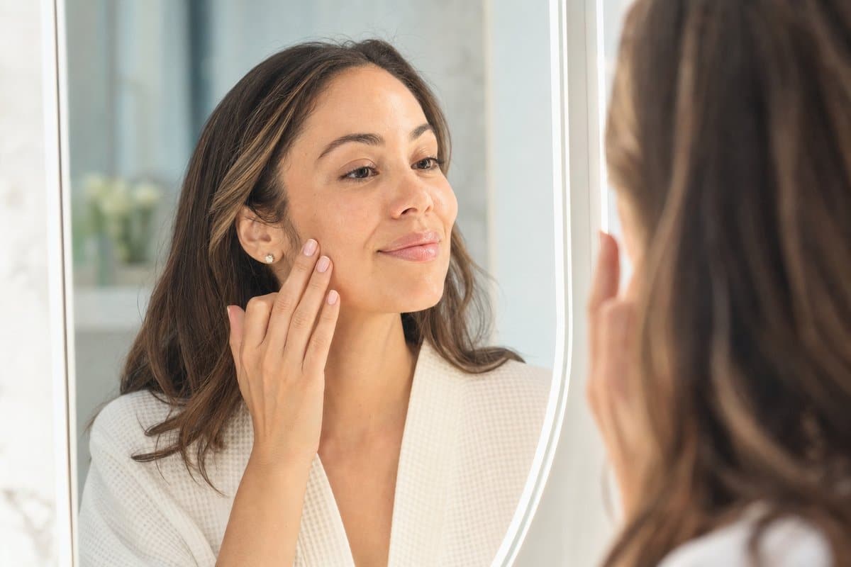 Woman admiring her clear even-toned cheeks after microneedling melasma treatment