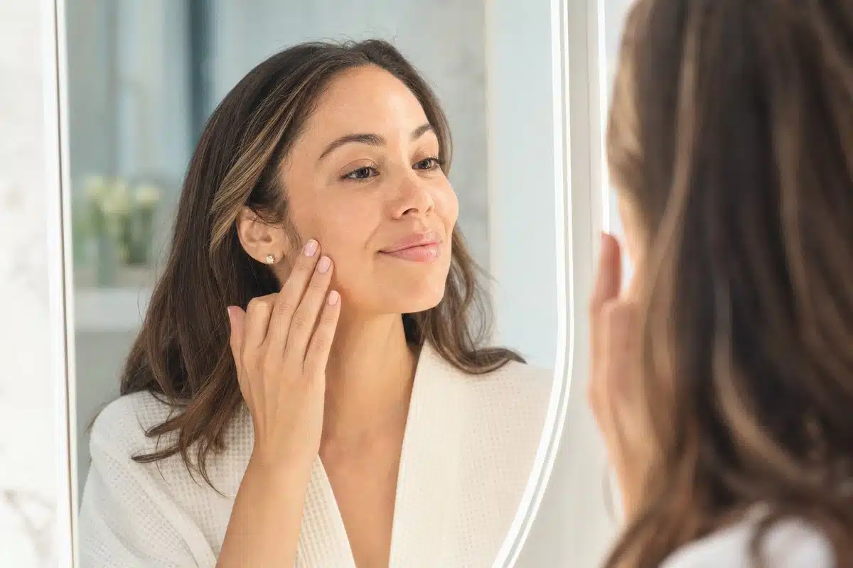 Woman admiring her clear even-toned cheeks after microneedling melasma treatment