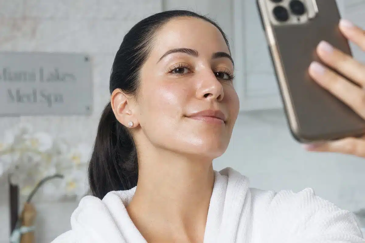 Young woman taking a selfie showing her clear, contoured cheeks and jawline after med spa treatment